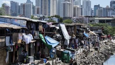 Shacks in the front with the skyline of Manila's financial district in the background