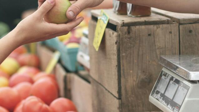 a hand purchasing an apple
